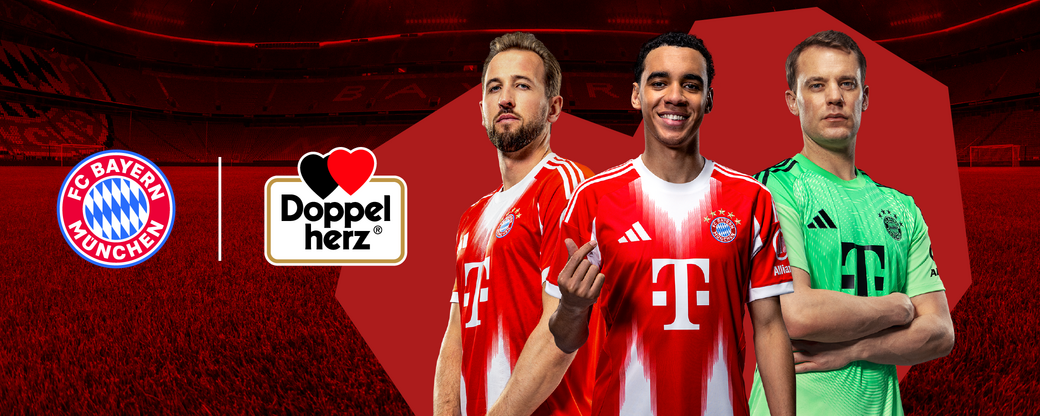 Rasmda FC Bayern München futbol klubi o'yinchilari ko'rsatilgan, ular qizil forma kiygan. O'ng tomonda boshqa figura, qizil fonda, "Doppel herz" logotipi joylashgan. Fon - stadion maydoni.