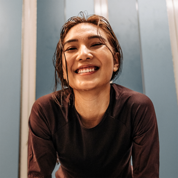 Rasmdagi ayolning tabassumi yorqin, uning sochlari nam va u sport kiyimida. U o'zini qulay his qilayotgandek ko'rinadi, tabiatdan xursandligi sezilib turibdi. Fon ranglari yumshoq, murakkabligi bilan ayolning holatini yoritmoqda.